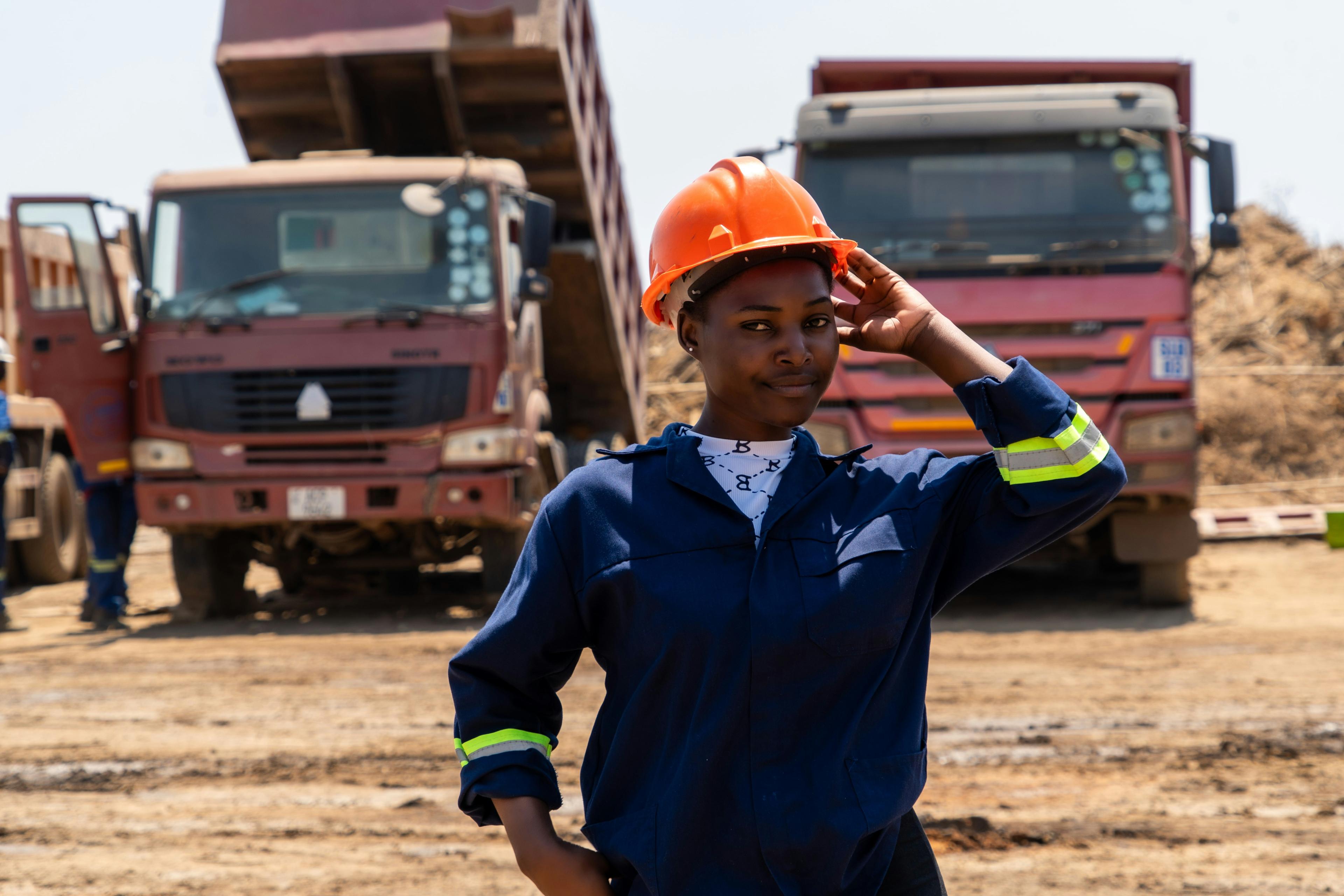 An engineer in a hard hat on site in front of heavy trucks